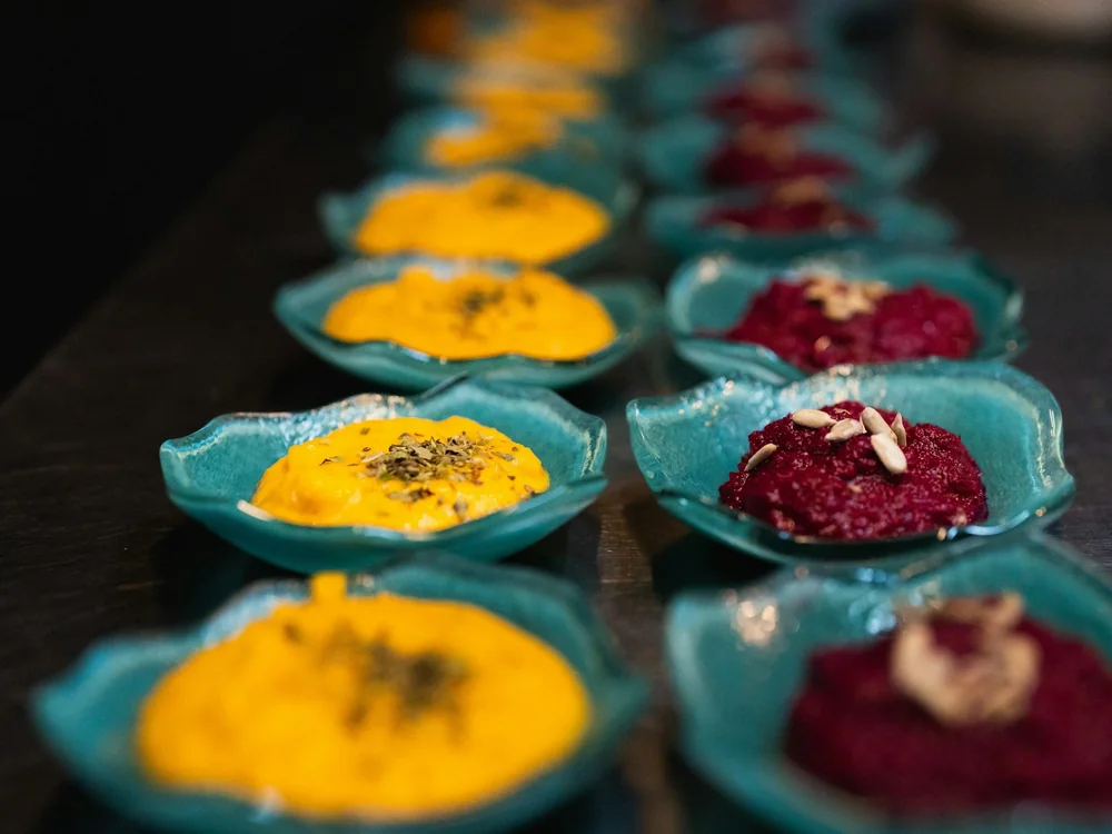 A row of small colourful plated dishes on turquoise ceramic dishes